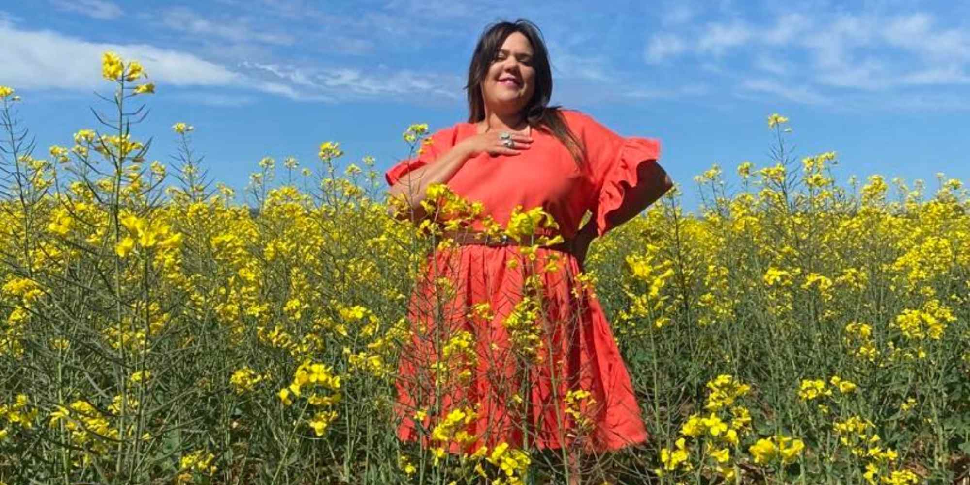 person in Curvature Clothing orange dress standing in a field