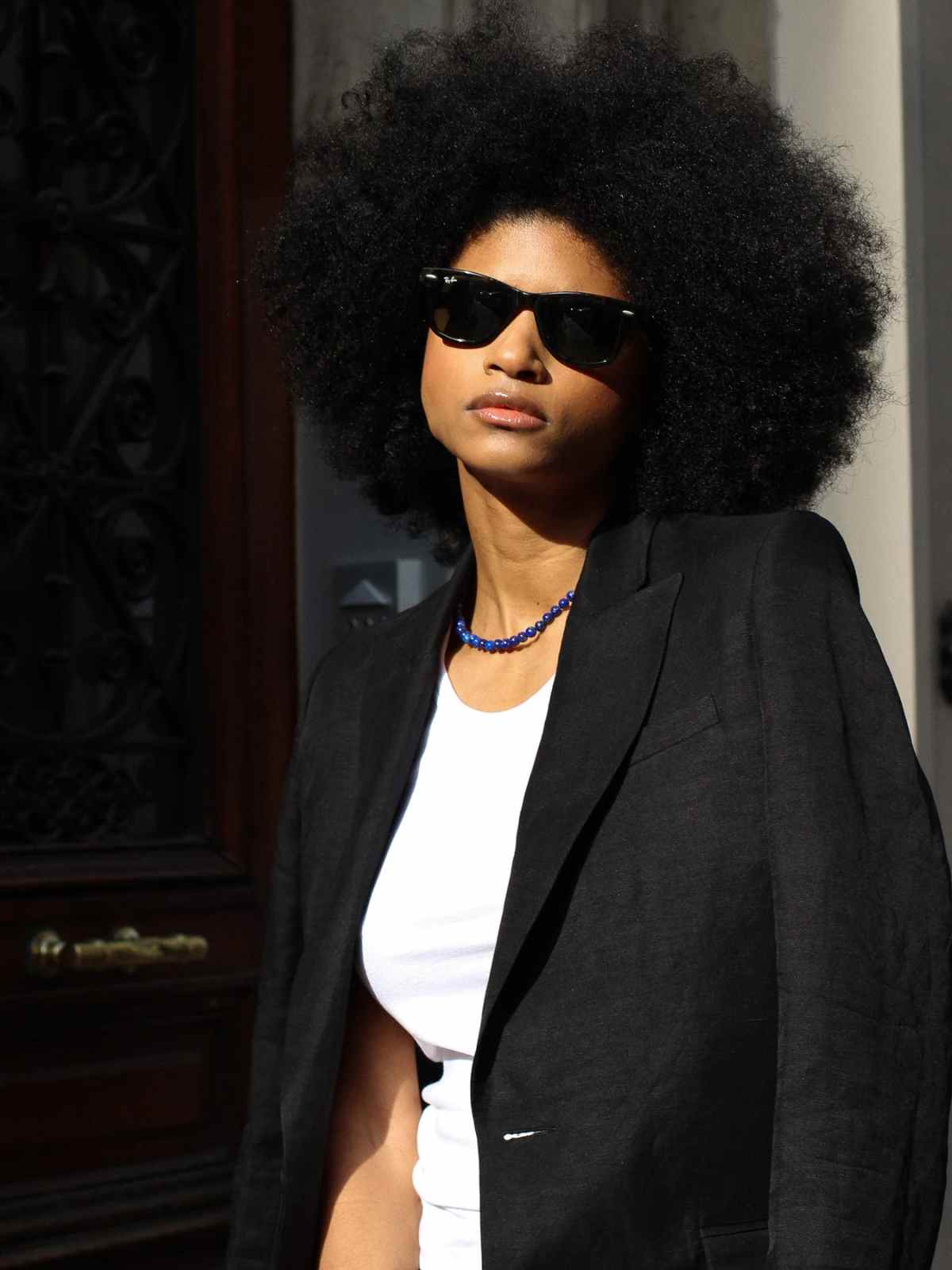 person wearing sunglasses and blazer from facettes studio