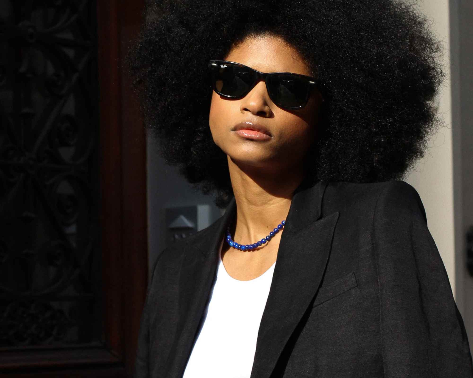 person wearing sunglasses and blazer from facettes studio