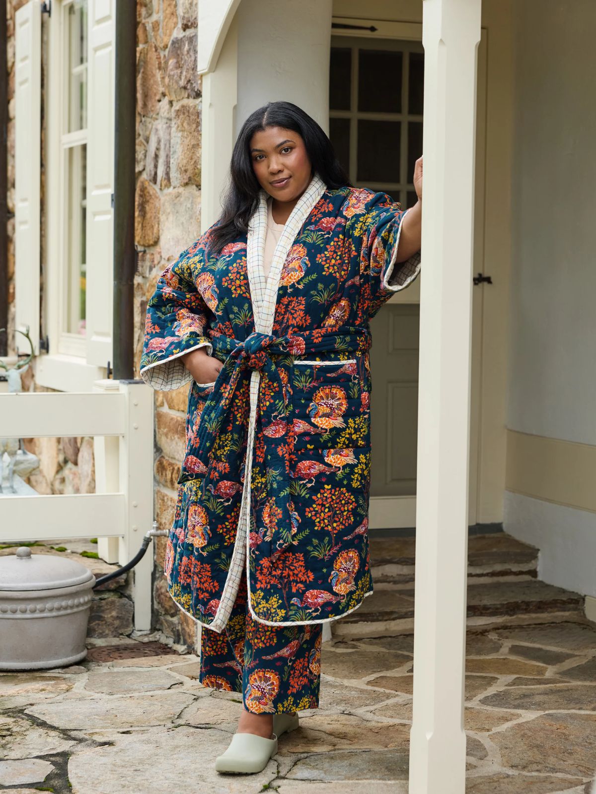 person standing on a porch wearing a printed robe