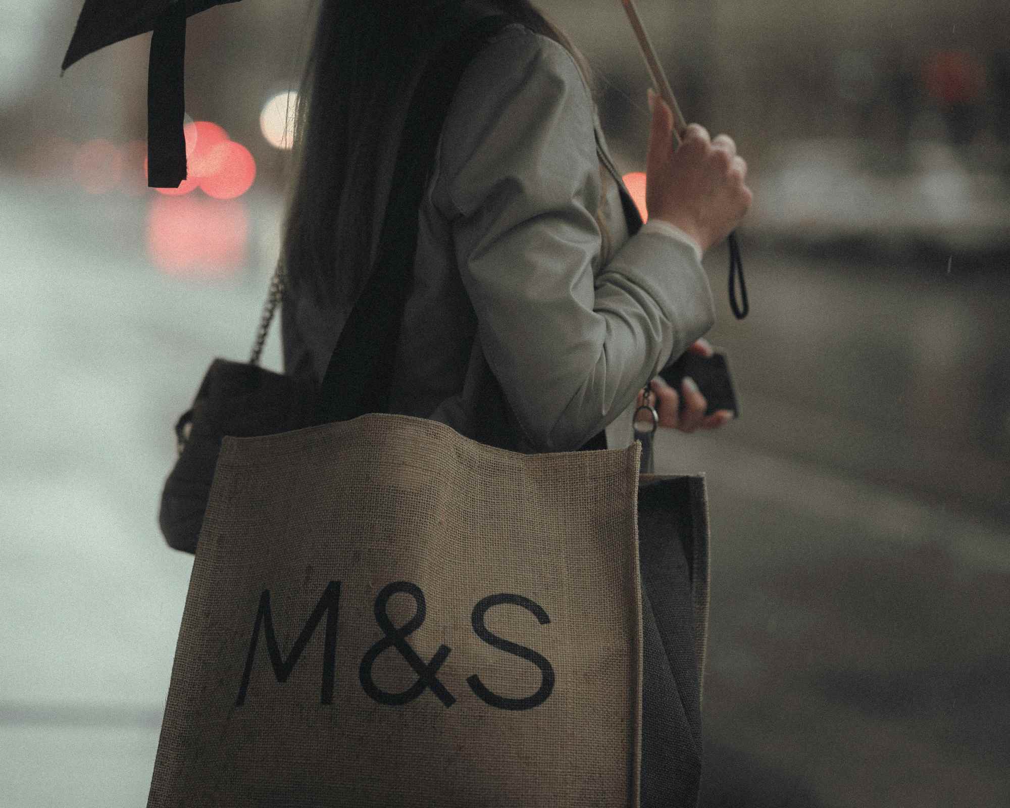 person carrying marks and spencer bag
