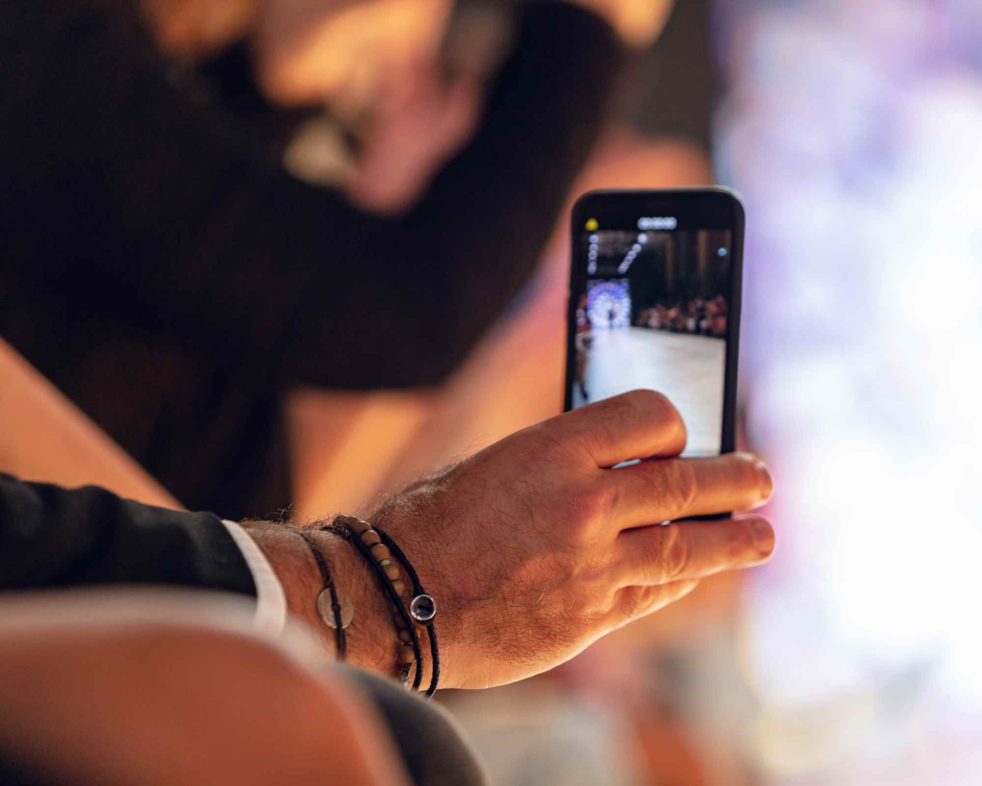 person's hand filming a fashion runway on an iphone